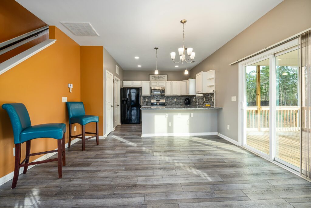 Spacious modern kitchen and living area with wooden floors and turquoise chairs.